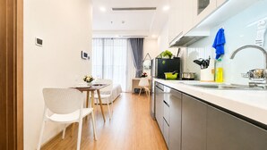 Een moderne keuken met roestvrijstalen apparatuur, een eethoek met witte stoelen en een houten vloer.