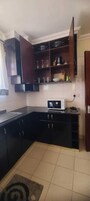 A compact kitchen with dark cabinetry, a microwave, and a tiled backsplash.