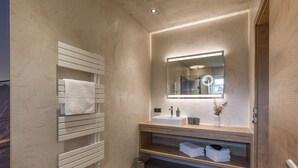 Un bagno moderno con un portasciugamani bianco, un lavabo rettangolare, uno specchio con illuminazione integrata e un piccolo cestino.