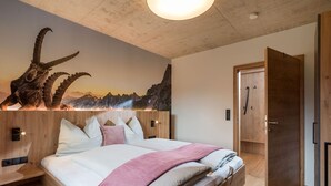 Una camera da letto moderna con un grande letto, una testiera in legno e un murale a tema montagna.