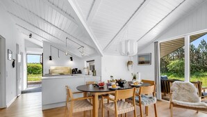 Une cuisine moderne avec un coin repas, un plancher en bois et de grandes fenêtres offrant une vue sur l’extérieur.