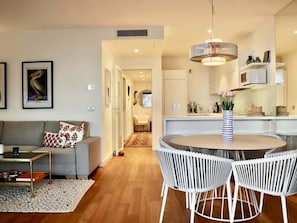 Un salon moderne comprenant un canapé, une table basse et un coin repas avec une table ronde et des chaises.