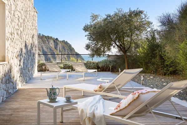 A wooden deck with lounge chairs, a table with a teapot, and a view of a mountainous landscape. - Gemma nel golfo di Trieste (Duino-Aurisina)