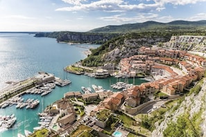 Une ville côtière dotée d’un port de plaisance, d’immeubles à étages et bordée de montagnes.
