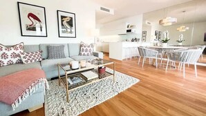 A modern living room with a sofa, coffee table, and dining area with chairs.