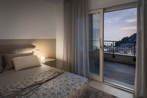 Et soveværelse med seng, natbord og udsigt til en balkon med gelænder.