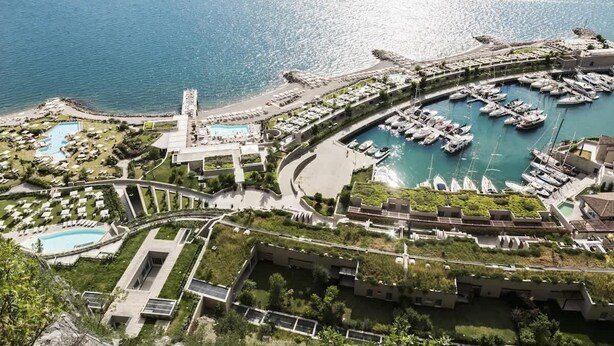 A coastal resort with a marina, swimming pools, and lush greenery.