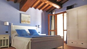 A bedroom with a bed, a nightstand, a wardrobe, and a window with curtains. - Villa Profidia (Gualdo Cattaneo)