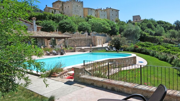 A swimming pool with lounge chairs, a stone building, and a castle in the background. - Villa Profidia (Gualdo Cattaneo)