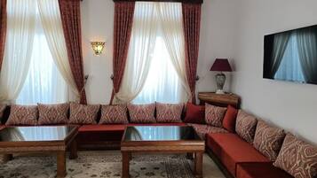 A living room with a sofa set, two coffee tables, a lamp, and a wall-mounted TV.