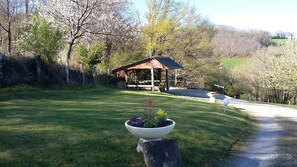Relax in a serene outdoor setting beneath a sloping roof, surrounded by lush greenery and vibrant flowers.