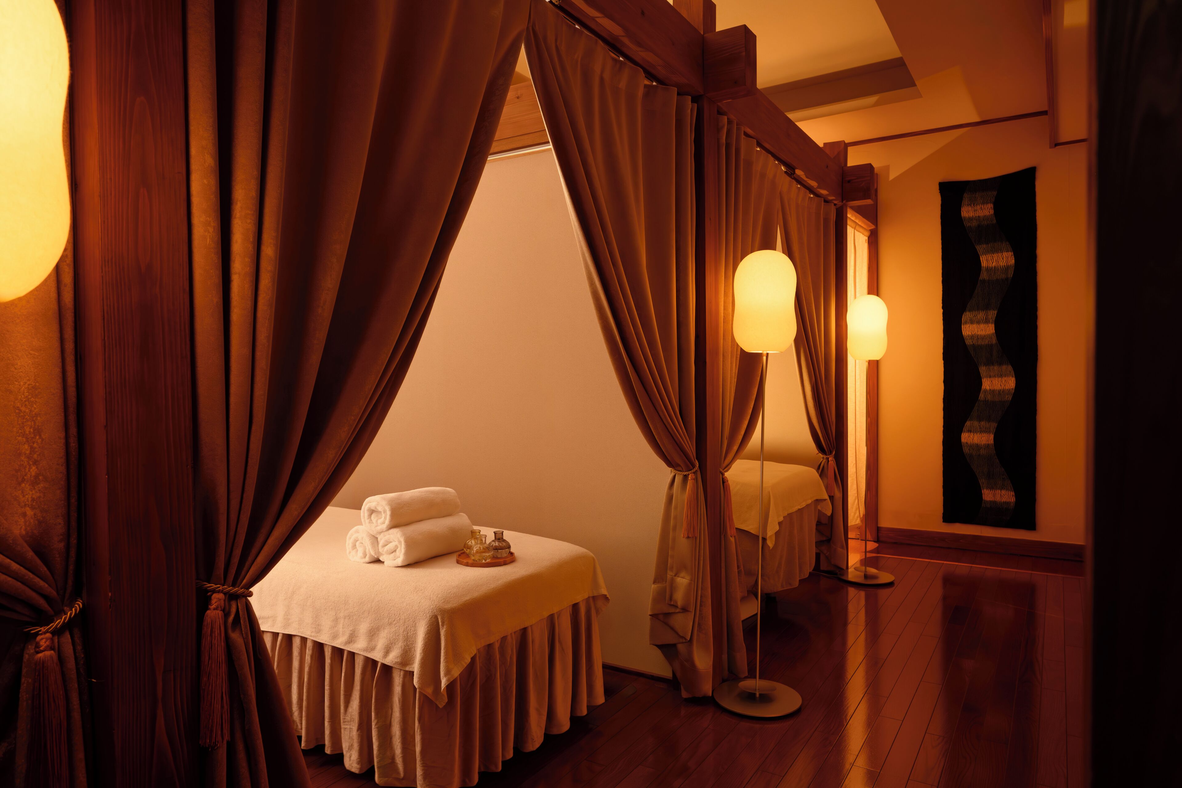A bedroom with a canopy bed, a bedside table with a lamp, and a large mirror.