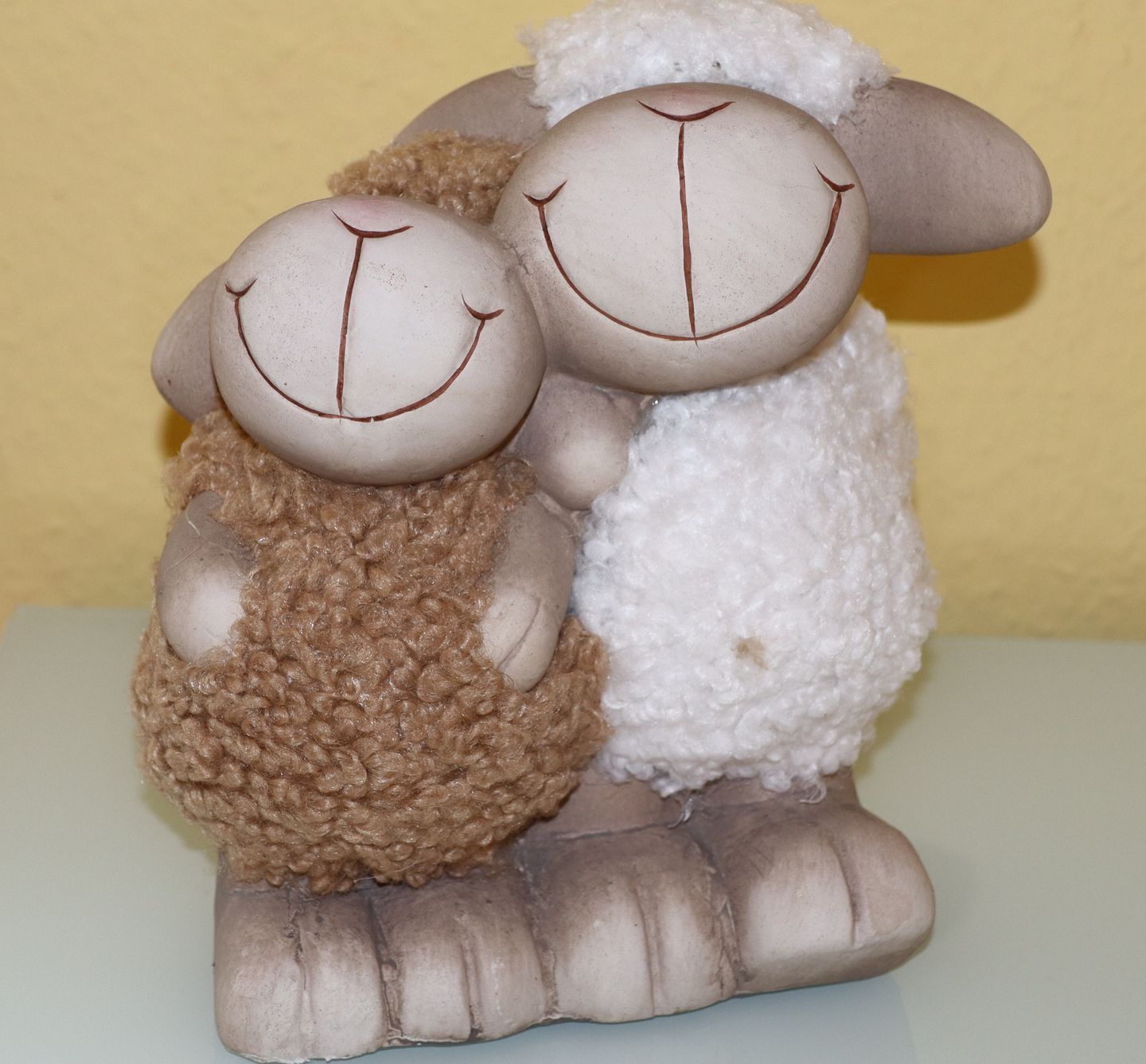 A figurine of two sheep sitting on a platform.