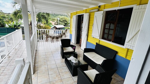 A covered outdoor seating area with wicker furniture and a view of the surrounding landscape.