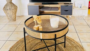 A living room with a TV, a wicker coffee table, and a decorative vase.