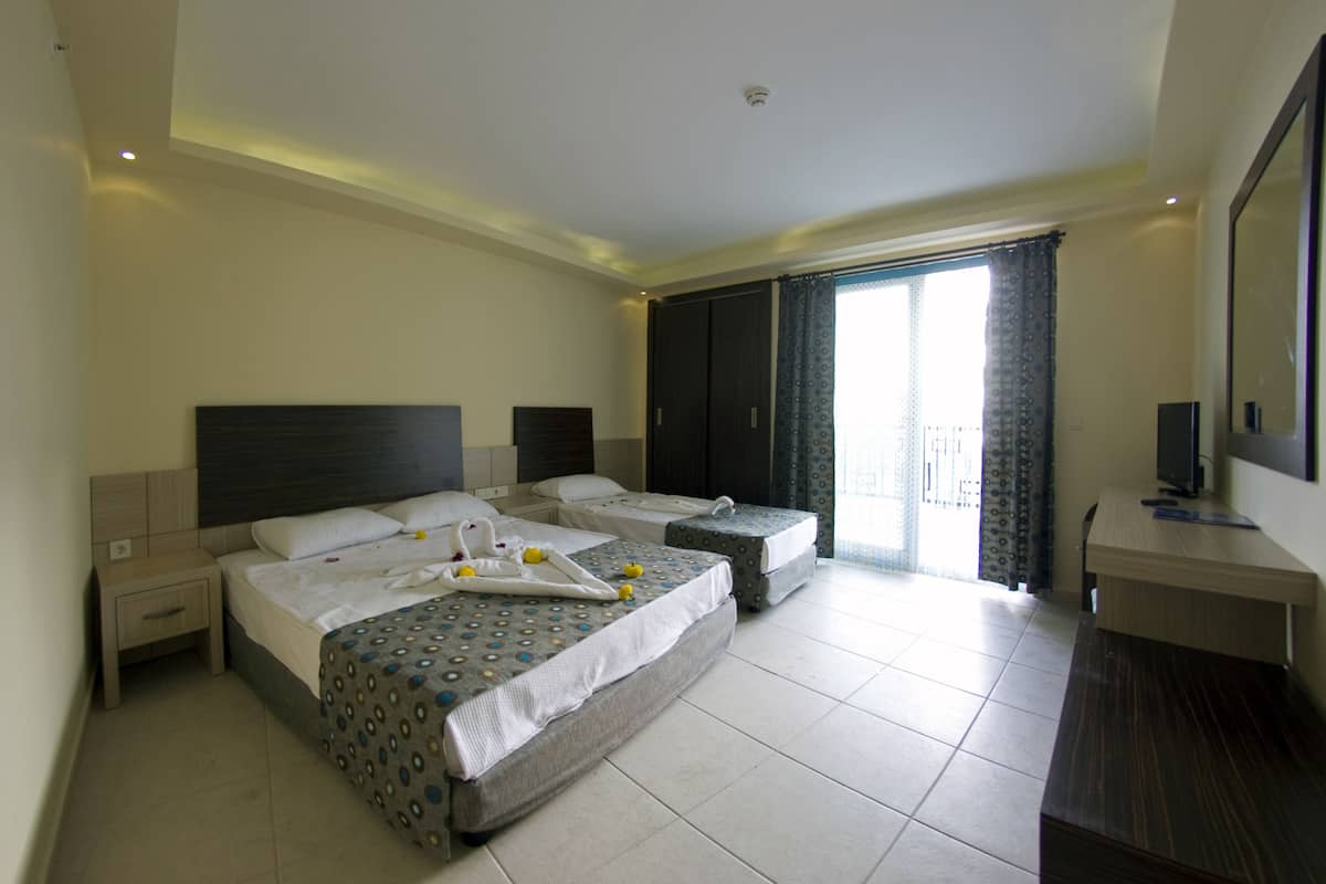 A hotel room with two beds, a desk, and a balcony.