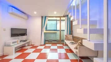 Una sala de estar moderna con piso a cuadros, un televisor de pantalla plana, un microondas, un sofá y una escalera.