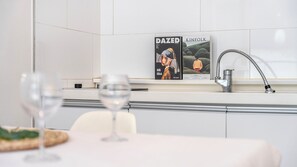 Une cuisine moderne, avec un numéro du magazine DaZed Kinfolk accroché au mur, un robinet en acier inoxydable et une table avec des verres.