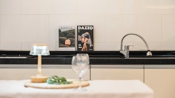 Una encimera de cocina con una copa de vino, una vela y dos revistas.