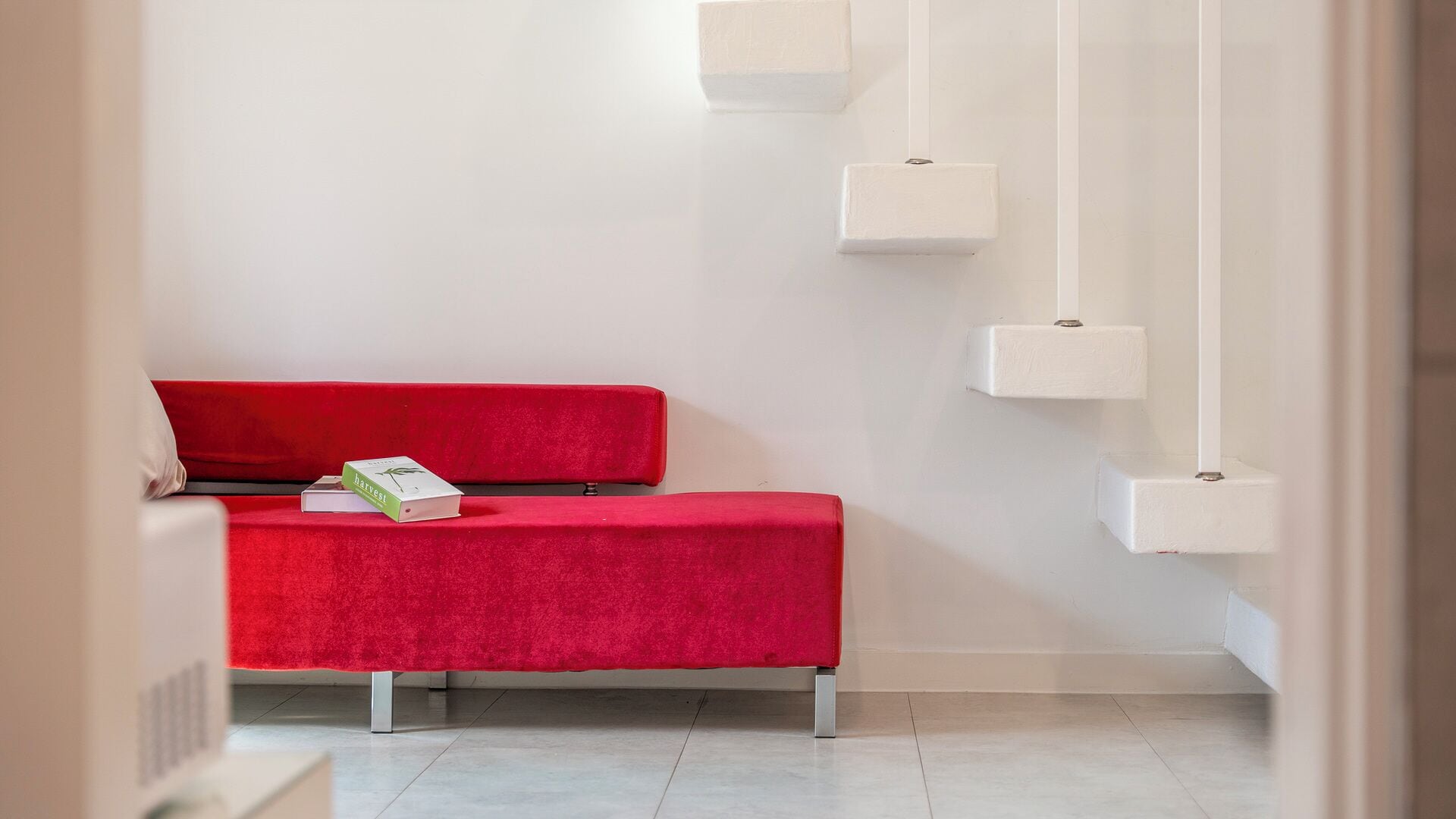 A room with a red sofa, a white wall, and a white floor.