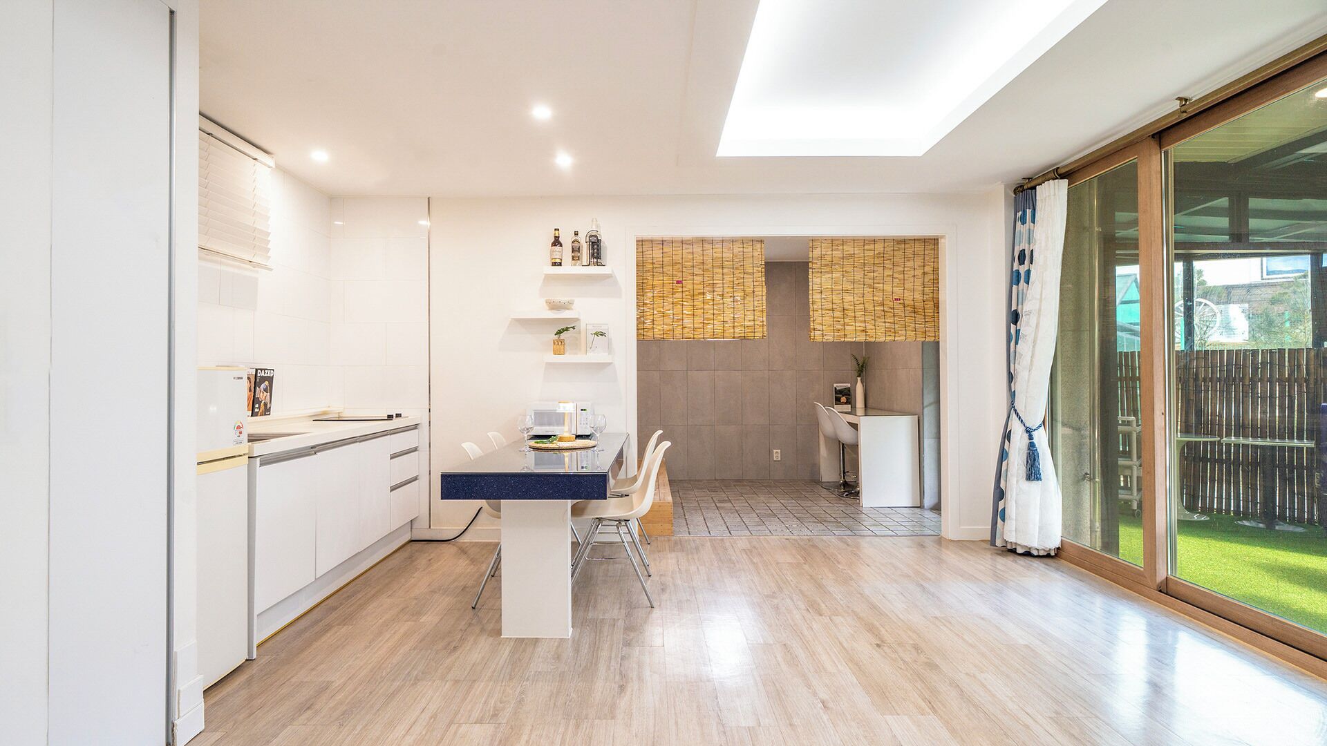 Una cocina moderna con comedor, horno empotrado y un amplio ventanal corredera que da a un patio.