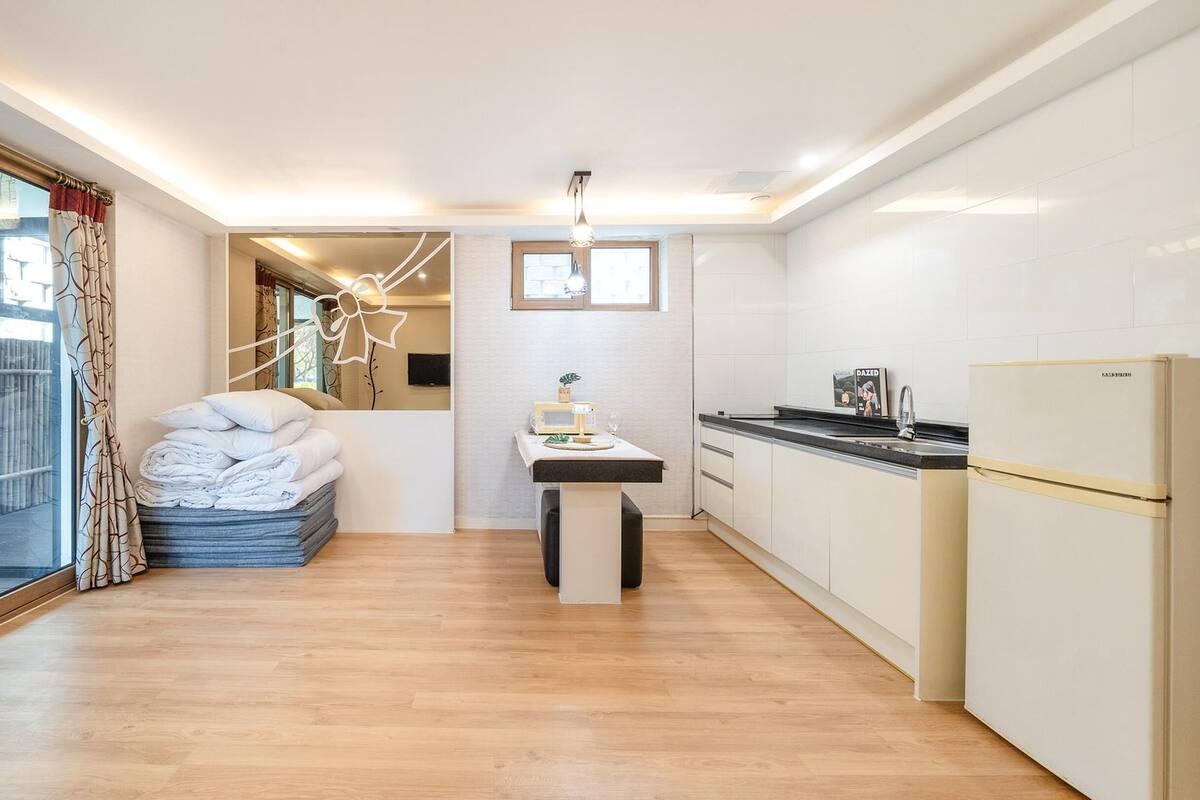 Eine moderne Küche mit Kühlschrank, Mikrowelle und Spüle. Ein Esstisch mit Stuhl und einer kleinen Pflanze darauf.
