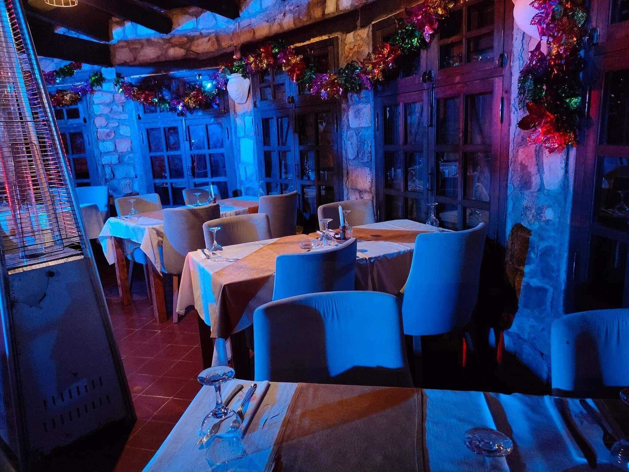En restaurang med dukade bord, en rustik stenmur och festliga dekorationer.