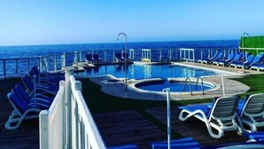 A pool area with lounge chairs and a view of the ocean. - Auberge Thais (Toudja)