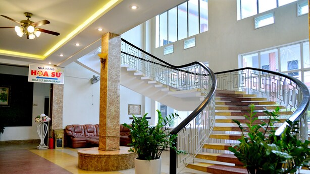 A modern interior with a spiral staircase, a sign for Hoa Su Restaurant, and potted plants. - Song Huong Hue Hotel (Hue)