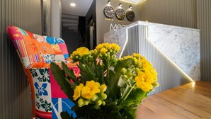Un interior moderno con una mesa de madera, cojines coloridos y un jarrón de flores amarillas.