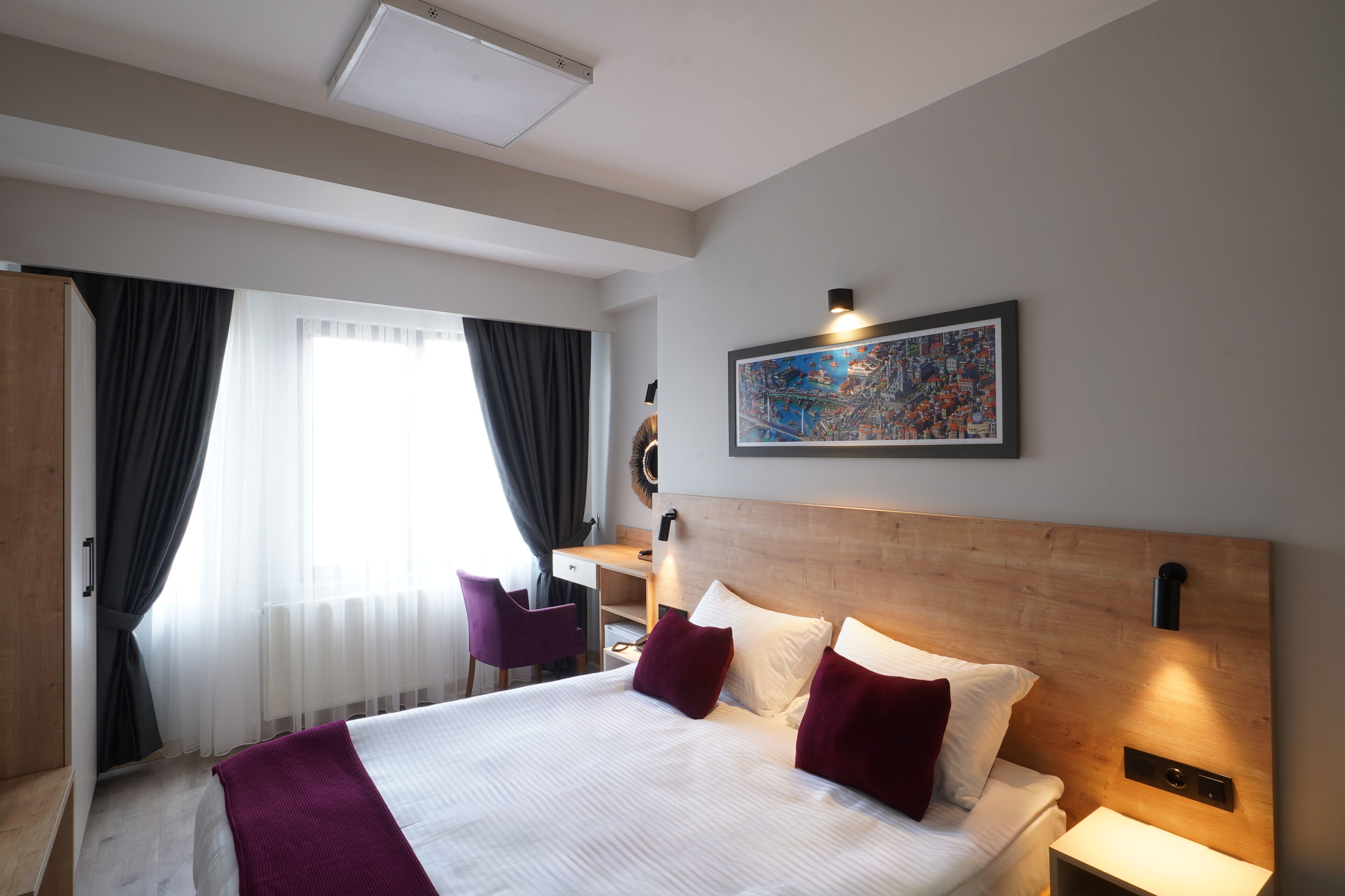 Une chambre d’hôtel avec un grand lit, un bureau, une chaise et un tableau au mur.