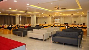 A spacious hall with rows of yellow chairs, a stage, and a red carpet. -  The Century Stays (Jaipur)