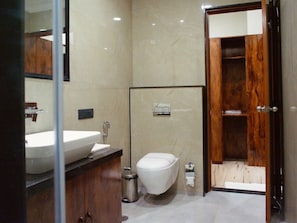 A modern bathroom with a large sink, toilet, and a wooden door leading to another room.
