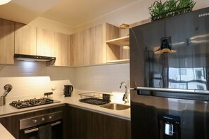 Eine moderne Küche mit einem Edelstahlkühlschrank, einem Gasherd und Holzschränken.
