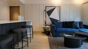 A modern living area with a bar, blue sofa, and black stools. - w* | Perfect 1BR w/ Great Deco in Barranco (Barranco)