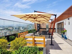 Eine Dachterrasse mit einer Holzbank, einem Tisch und einem Sonnenschirm.