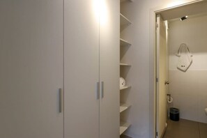 A bathroom with a toilet, a trash bin, and a towel hanging on the wall.