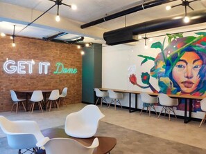 Ein modernes Café-Interieur mit einer Neonreklame, Wandmalerei und zeitgemäßer Sitzmöbel.