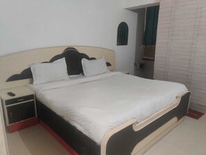 Ein Einzelbett mit Kopfteil, ein Nachttisch und eine Wand-Klimaanlage.