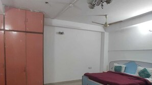 A bedroom with a bed, a wardrobe, a ceiling fan, and a light fixture. - Hotel Abhishek Residency By The Arrow (New Delhi)
