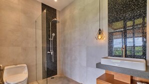 A modern bathroom with a glass-enclosed shower, a white toilet, a wooden vanity with a mirror, and a sink. - Villa Dharman B7 (Ubud)