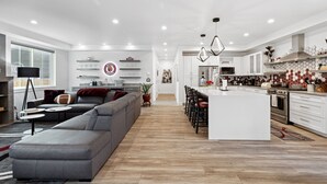 A modern kitchen with white cabinets, a central island, and a dining area with bar stools.