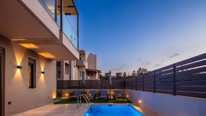 A modern pool area with a clear blue pool, a metal ladder, and lounge chairs. - Modern facilities, walking distance to the beach! (Panormo)