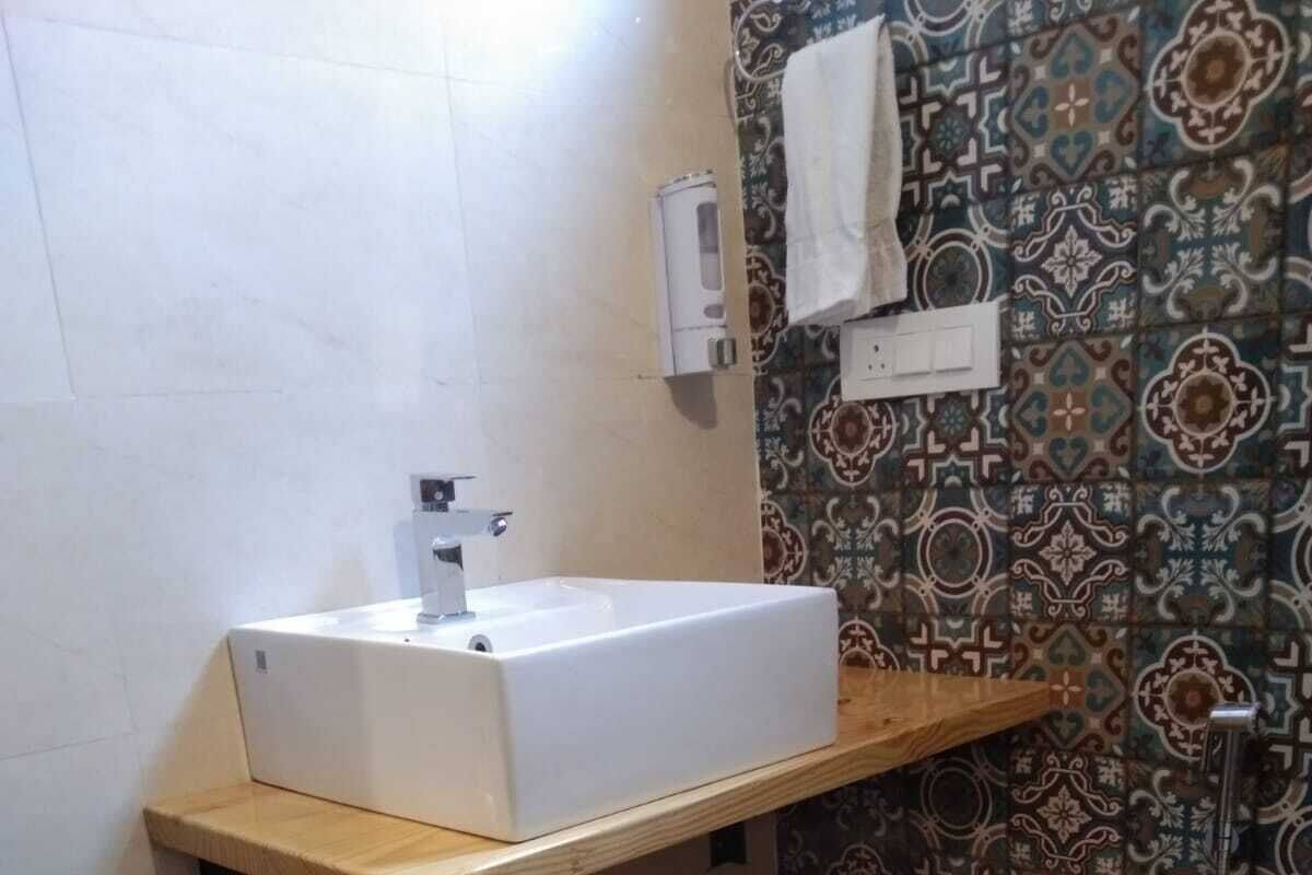 A bathroom with a white sink, a towel rack, and patterned tiles.