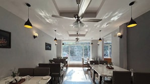 Un comedor moderno con techos altos, iluminación colgante y piso de baldosas estampadas.