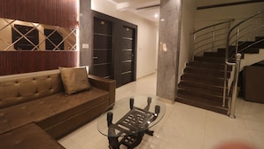 Una sala de estar moderna con una mesa de centro de vidrio, un sofá marrón y una escalera.
