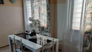 Spisestue med et hvidt bord og stole, en vase med hvide blomster og en mikrobølgeovn på bordet.