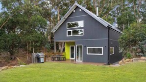 A modern two-story house with a dark exterior, a green door, and a patio with outdoor furniture. - Serenity at Ridgeway Retreat Relax Hike Bike (Ridgeway)