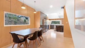 A modern kitchen with wooden cabinetry, a central island, and pendant lighting. - Serenity at Ridgeway Retreat Relax Hike Bike (Ridgeway)