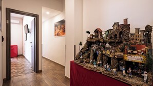 A hallway with a red suitcase, a wooden floor, and a model display on a table. - PIGNASECCA GUEST HOUSE  (Naples)